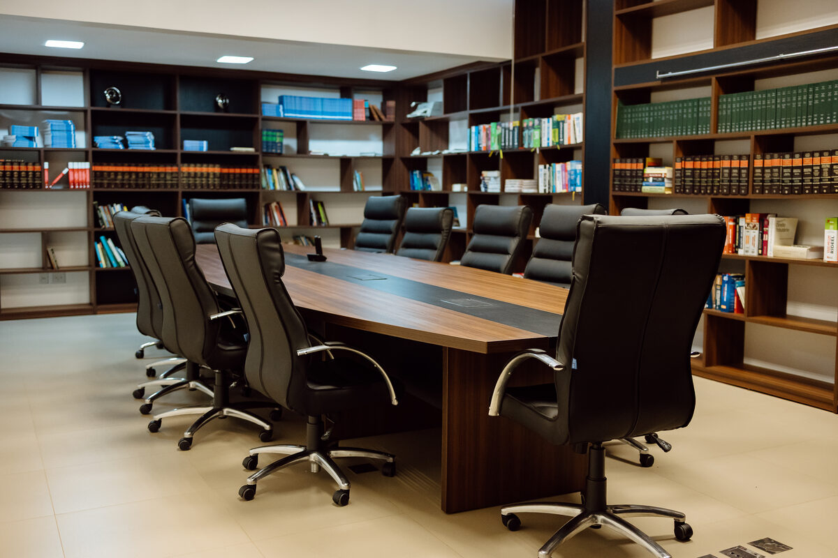 Sala de reuniões da Recon, com mesa de diretoria e biblioteca técnica de contabilidade e direito ao fundo